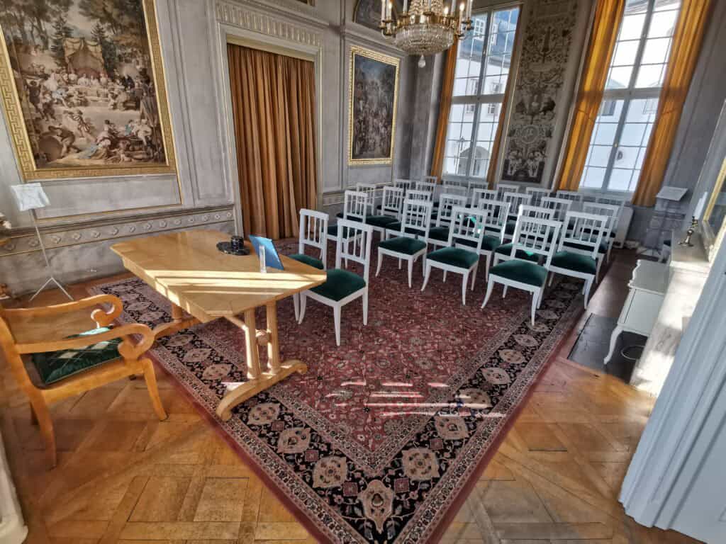 Kleiner Trausaal mit 1 Tisch und mehreren weißen Stühlen