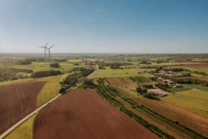Vogelperspektive über dem Ort Wildenfels. Es sind Landflächen, zwei Windräder und Häuser zu sehen