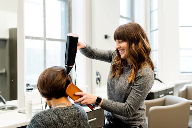 Auf dem Bild sind zwei Personen in einem Friseursalon zu sehen