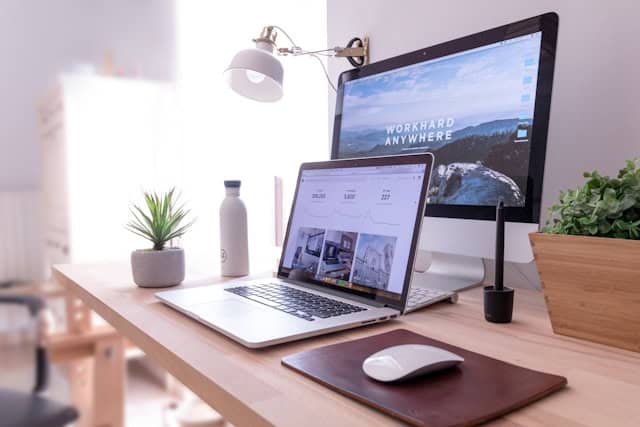 Auf dem Bild ist ein Arbeitsschreibtisch mit einem Laptop und iMac zu sehen