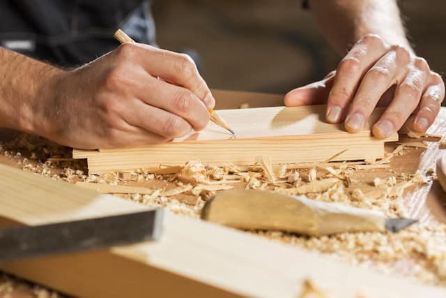 Auf dem Bild ist ein Stück Holz zu sehen, welches bearbeitet wird